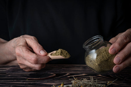 Dried medicinal herb, antiparasitic collection of tansy, wormwood and cloves (troychatka). The herbalist pours the crushed collection into a jar. high quality photoの写真素材