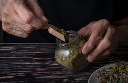 Dried medicinal herb, antiparasitic collection of tansy, wormwood and cloves (troychatka). The herbalist pours the crushed collection into a jar. high quality photoの写真素材