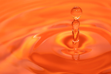 Circles on the water from a fallen drop of water. Orange, golden background. high quality photoの写真素材