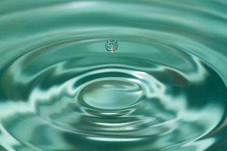 Photo of circles on the water from a fallen drop of water. Blue, aquamarine background. high quality photoの写真素材