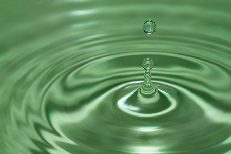 Photo of circles on the water from a fallen drop of water. green background. high quality photoの写真素材