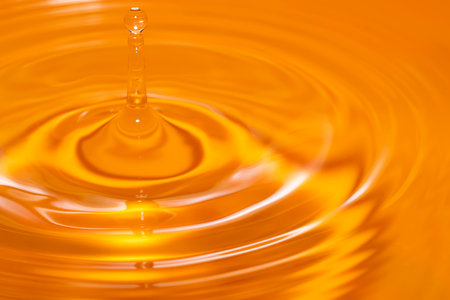 Circles on the water from a fallen drop of water. Yellow, golden background. high quality photoの写真素材
