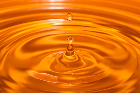 Circles on the water from a fallen drop of water. Yellow, golden background. high quality photoの写真素材