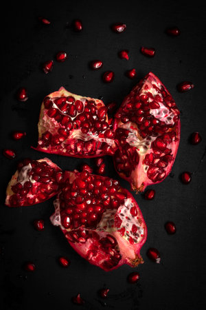 Pomegranate broken into pieces, on a black background. high quality photoの写真素材