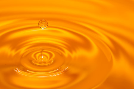 Circles on the water from a fallen drop of water. Yellow, golden background. high quality photoの写真素材