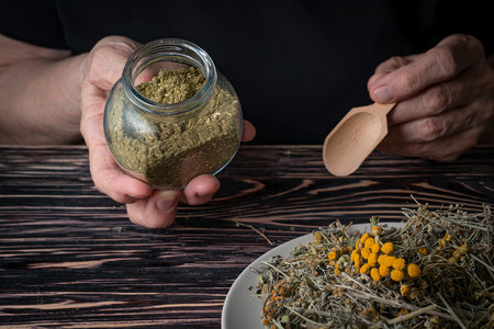 Dried medicinal herb, antiparasitic collection of tansy, wormwood and cloves (troychatka). The herbalist pours the crushed collection into a jar. high quality photoの写真素材