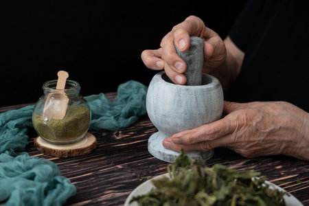 An herbalist prepares a powder from dried May nettle leaves. Folk, alternative medicine. high quality photoの写真素材