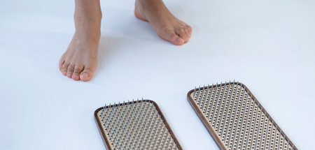 The girl is preparing to stand on the board with nails. Nailing on boards of sadhus. high quality photoの写真素材
