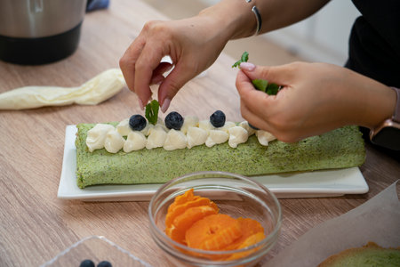 A woman decorates a pistachio roll with berries. Master class on cooking desserts. high quality photoの写真素材