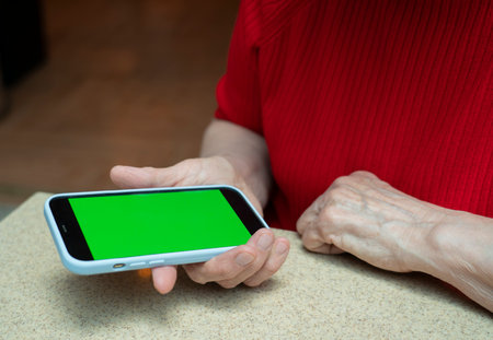 Phone with a green screen in the arm of an elderly woman of retirement age. high quality photoの写真素材
