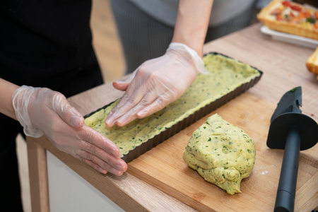 Cooking quiche with salmon. A woman puts spinach dough into a pie pan. high quality photoの写真素材