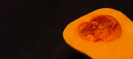 Pumpkin in a cut in the shape of a heart on a black background. Banner with place for text. high quality photoの写真素材
