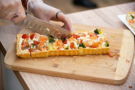 Master class in cooking. Ready quiche with salmon, broccoli and tomatoes is cut into portions. high quality photoの写真素材