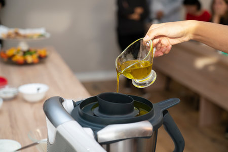 Master class in cooking. A cook pours oil into a food processor (blender) to make a salad dressing. high quality photoの写真素材