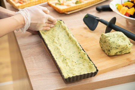 Cooking quiche with salmon. A woman puts spinach dough into a pie pan. high quality photoの写真素材