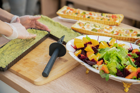 Cooking quiche with salmon. A woman puts spinach dough into a pie pan. high quality photoの写真素材