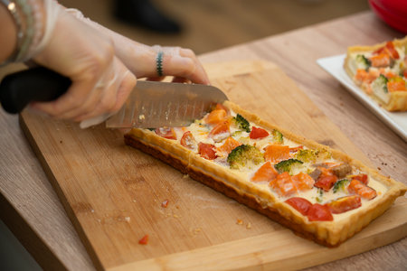 Master class in cooking. Ready quiche with salmon, broccoli and tomatoes is cut into portions. high quality photoの写真素材