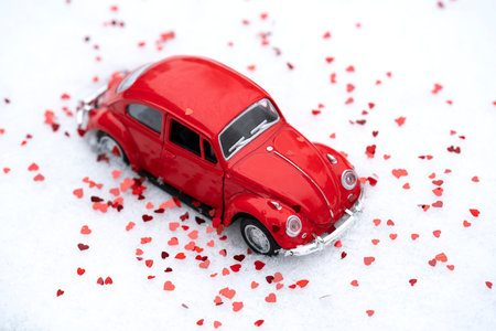 Red toy retro car on snow with glitter hearts. Background, postcard for Valentine's Day. high quality photoの写真素材