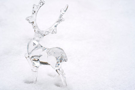 Transparent figurine of a deer made of acrylic on the snow. Background, postcard with place for text. high quality photoの写真素材