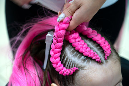 The process of braiding fashionable braids from bright pink and blue kanekalon for a girl. back to school. Braid studio. high quality photoの写真素材