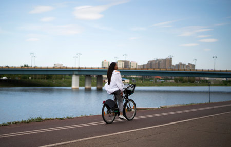 Nur-Sultan, Kazakhstan, May 25, 2022. A young brunette girl rides along the promenade on a rented bike. high quality photoの写真素材