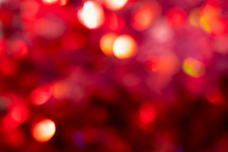 Multicolored bokeh on a red blurred background. Multicolored bokeh on a red blurred background. Festive background can be used for postcards for New Year, Christmas, Valentine's Day.の写真素材