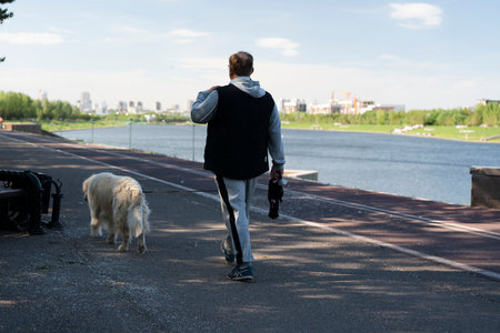 An elderly man walks with a dog on the street along the embankment. high quality photoの写真素材