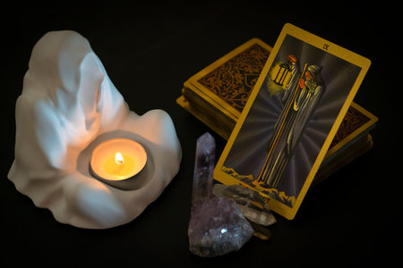 Gold embossed tarot cards, candle in a plaster candlestick and natural crystals on the table. The Major Arcana card The Hermit lies facing the viewer. high quality photoの写真素材