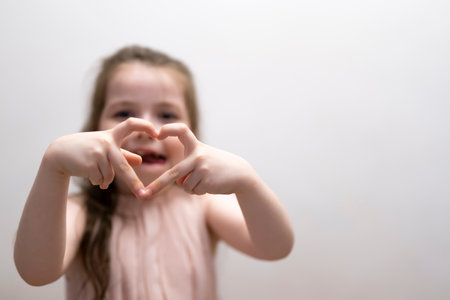 A girl, a brunette of seven years, shows the figure of a heart with her hands. high quality photoの写真素材
