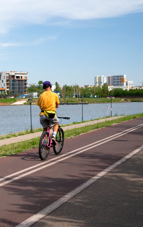 Nur-Sultan, Kazakhstan, June 2022 A guy with headphones on his head rides a bicycle along the bike path.のeditorial素材