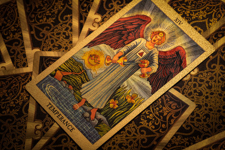 Astana, Kazakhstan, April 2023. Gold embossed tarot cards on the table. The Major Arcana card The Temperance lies facing the viewer.のeditorial素材