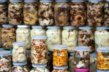 Pickled mushrooms (chanterelles, milk mushrooms, porcini mushrooms) in jars on the counter. small...