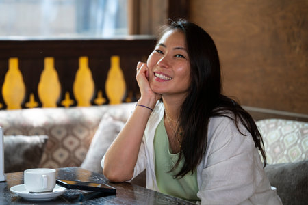 A beautiful Asian girl (Kazakh) is sitting on the terrace of an oriental cafe. Summer portrait of a...