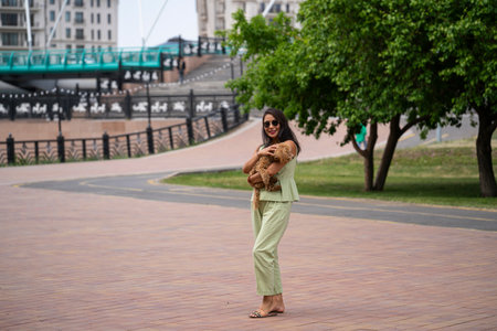 A beautiful Asian girl (Kazakh) holds a dog (mini poodle) in her hands. The girl has emotions of happiness and joy on her face. high quality photoの写真素材