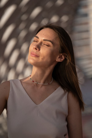 Summer portrait of a young brunette woman in a beige outfit. Urban abstract background, beautiful refraction of natural light. high quality photoの写真素材