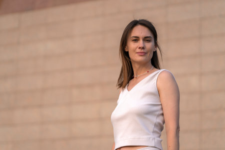 Summer urban portrait of a young brunette woman against a beige (brown) color wall. high quality photoの写真素材