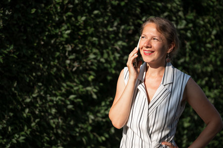 Young blonde woman talking on a smartphone on a city street. high quality photoの写真素材