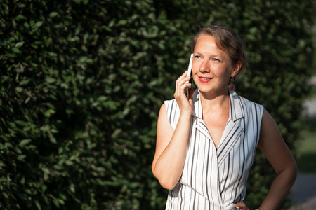 Young blonde woman talking on a smartphone on a city street. high quality photoの写真素材