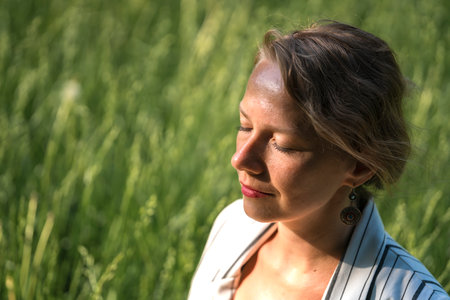 A young blonde woman meditates on the grass in the park during a lunch break. high quality photoの写真素材