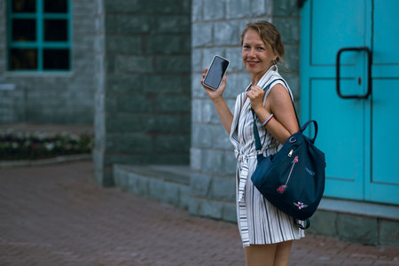 Young blonde woman talking on a smartphone on a city street. high quality photoの写真素材