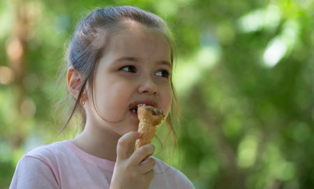 Summer portrait of a girl of seven years old who eats ice cream in a waffle cup. high quality photoの写真素材