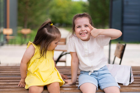 Portrait of sisters 2 and 6 years old outdoors in the park. Relationships between children in the...