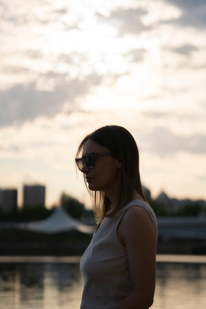 Silhouette of a young woman in sunglasses against the sunset sky. high quality photoの写真素材