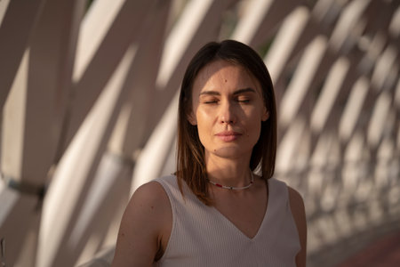 Summer portrait of a young brunette woman in a beige outfit. Urban abstract background, beautiful refraction of natural light. high quality photoの写真素材