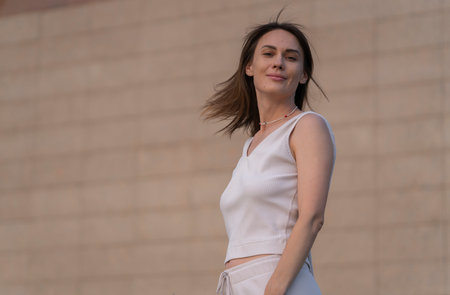 Summer urban portrait of a young brunette woman against a beige (brown) color wall. high quality photoの写真素材