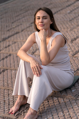 Summer urban portrait of a young woman. A woman sits on the embankment and thinks about something. high quality photoの写真素材