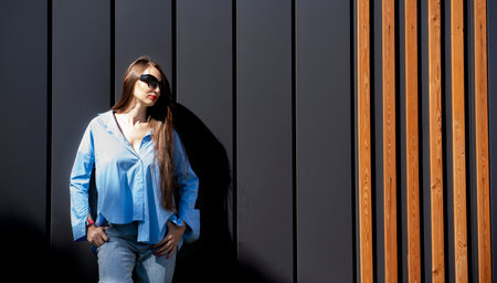 Summer portrait of a girl with long blond hair in sunglasses. A girl in a blue shirt and blue jeans...