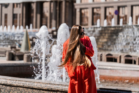 Summer portrait of a girl with long blond hair. Girl in orange clothes and sunglasses. The girl turns her head and her hair flutters in the wind. High quality photoの写真素材