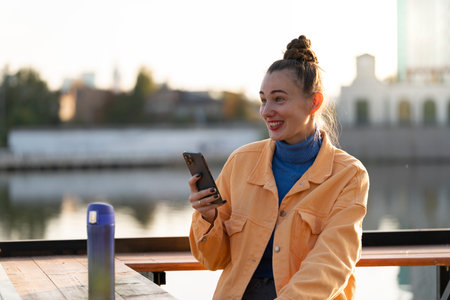 A young woman with a smartphone in her hands on the street in autumn. High quality photo