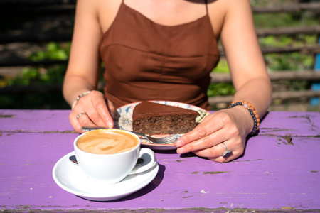 A girl with a cup of cappuccino with coconut milk and a chocolate raw food, vegetarian cake. High quality photoの写真素材